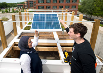 Students on roof of Mason's Merten Hall with solar grid, plants to hold water