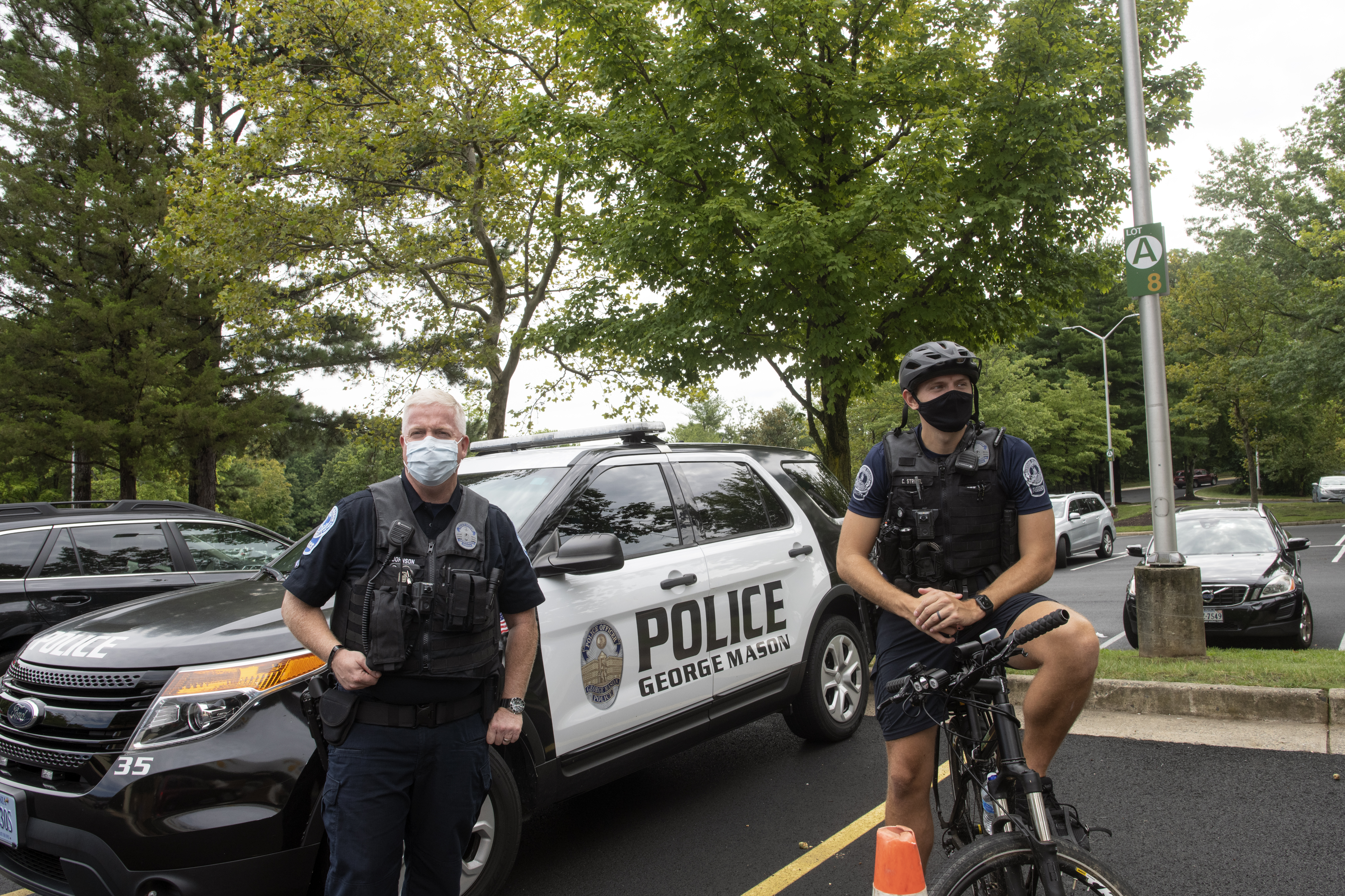 Mason police officers, one in front of patrol car, on one bicycle