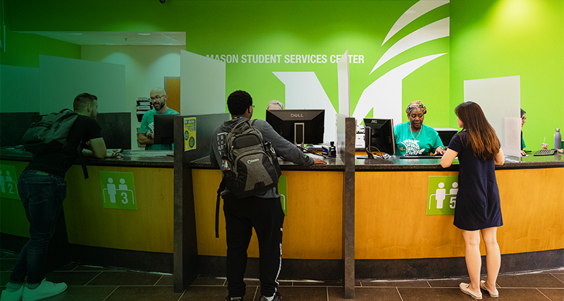 Students stand at the counter of the Mason Student Services Center