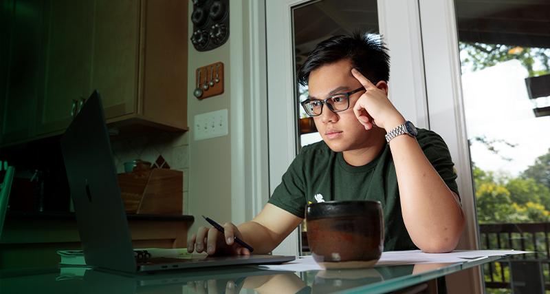 A Mason student works on their laptop at home