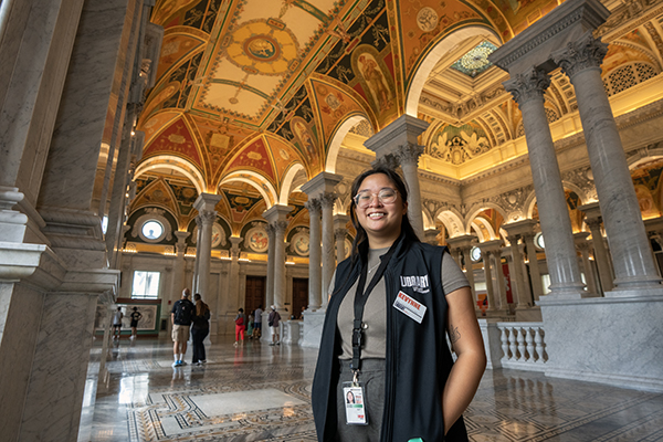 Kevynne stands inside the Library of Congress wearing her work vest and ID.