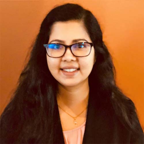 Southeast Asian woman smiles warmly in her glasses