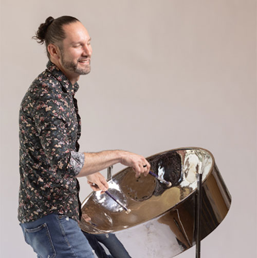 Victor Provost jamming on his steel pan wearing a patterned shirt