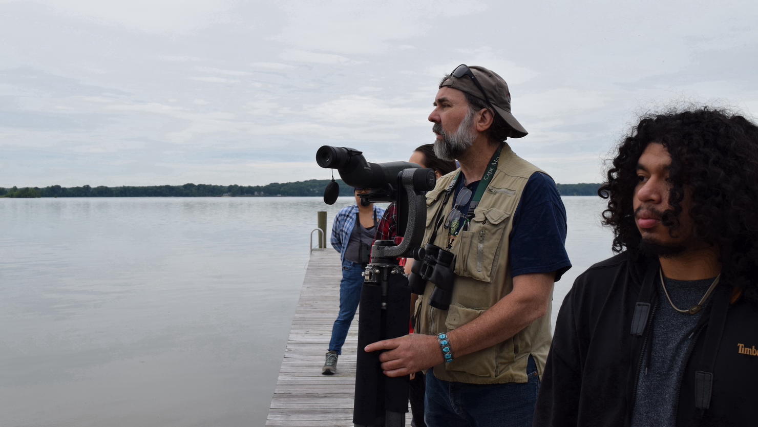 Dr. Tom Wood and Brian Jiménez during a wildlife assessment. Dr. Wood is using a spotting scope on a gimbal and looking out across a body of water.