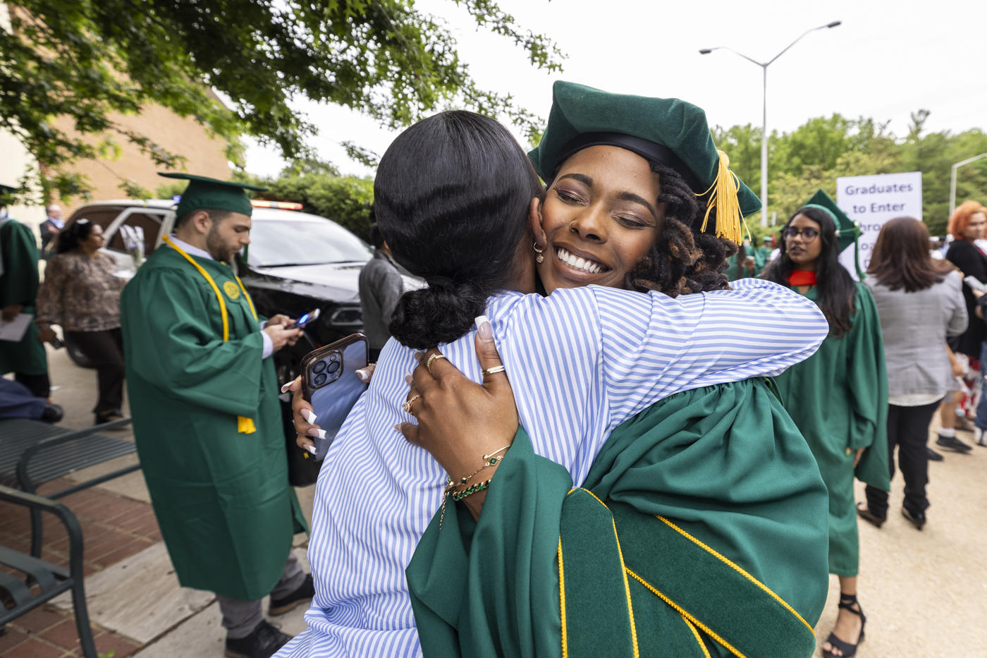 Graduate embraces a loved one outside after the ceremony