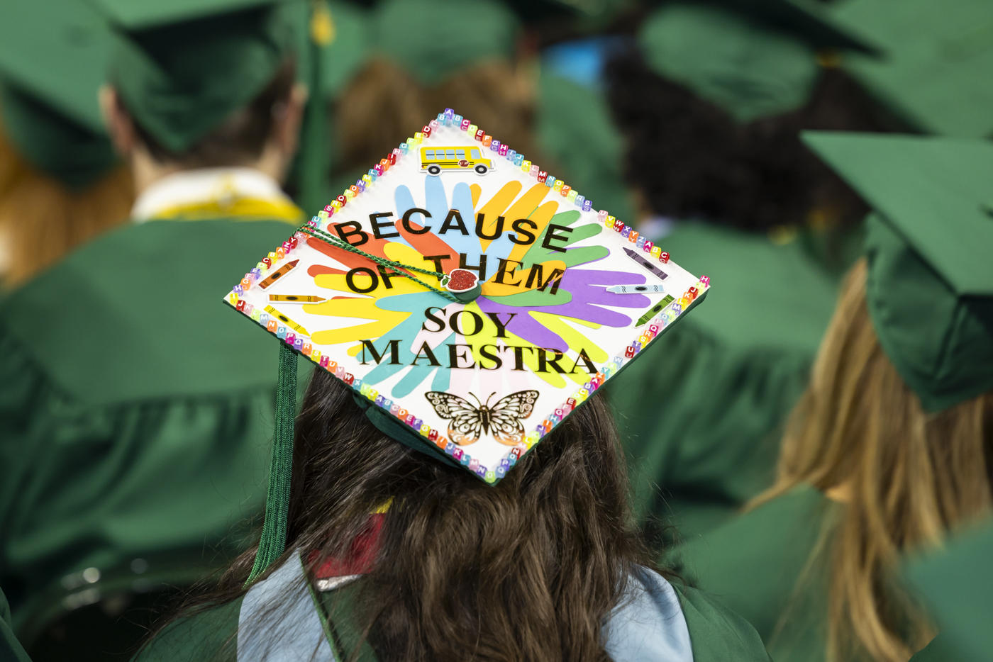 Graduation cap is decorated to say "Because of them soy maestra"