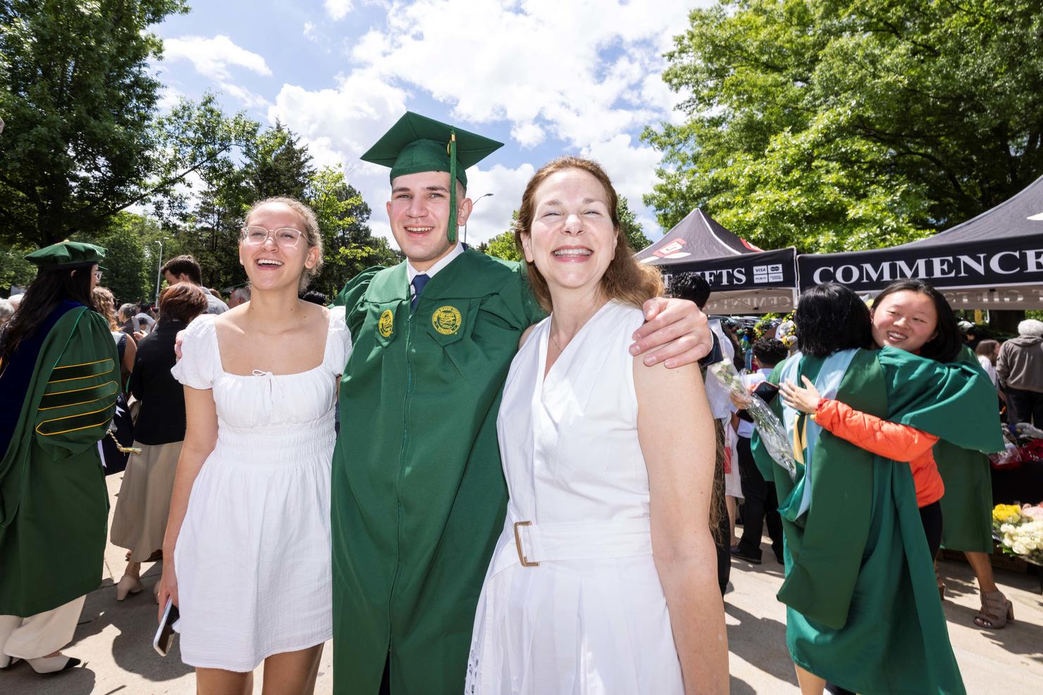 Graduate puts his arms around two family members outside EagleBank Arena