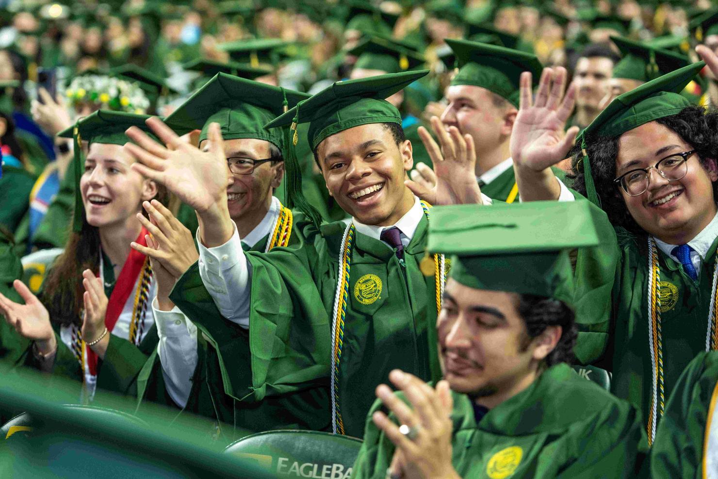 Graduates excitedly wave and smile during Commencement ceremony