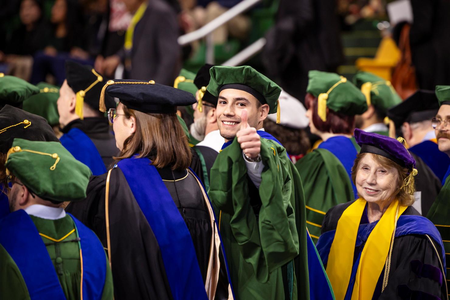 A graduating student turns around and gives a thumbs up