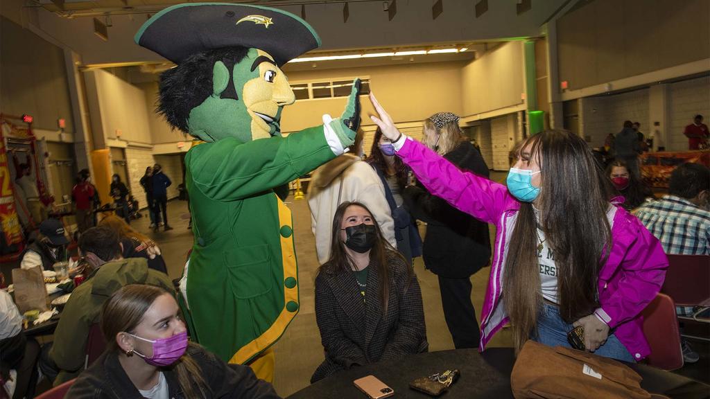 Mason mascot, The Patriot, high fives a student at the Homecoming Tip Off Party celebration