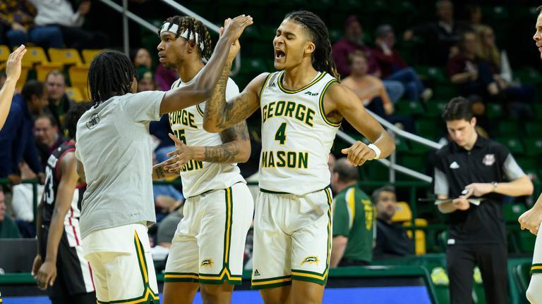 two Mason basketball team members high five each other after scoring 