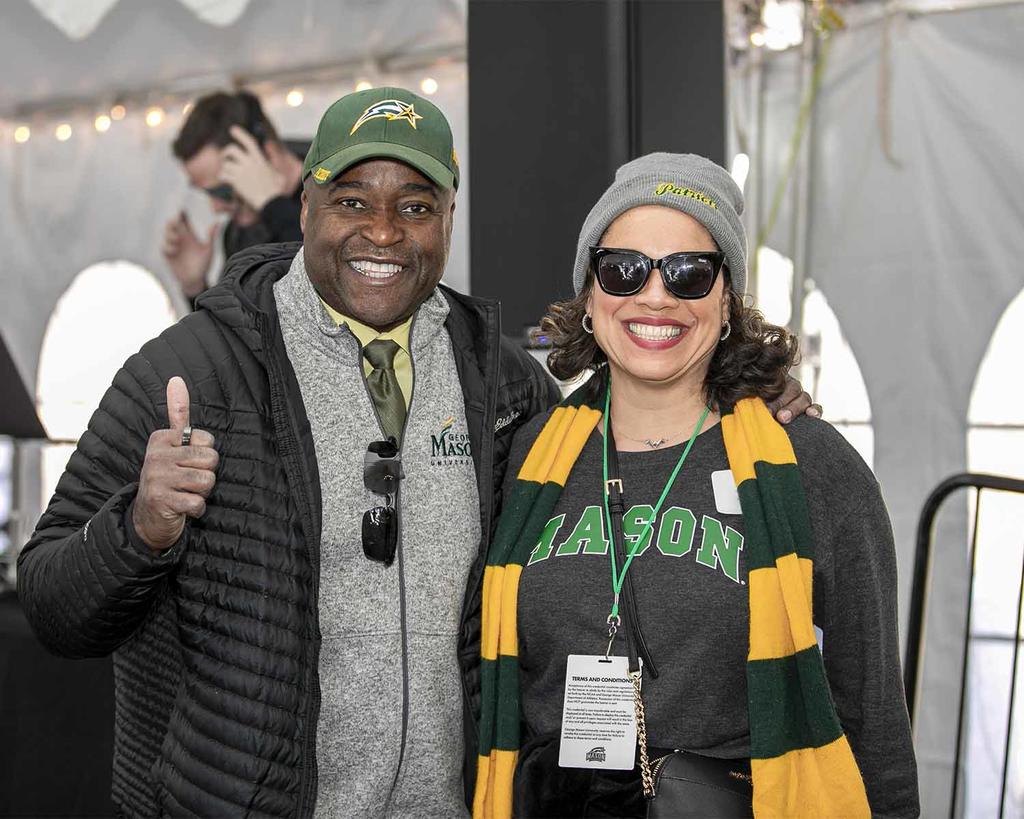 Dr. Washington standing next to a Mason Alum wearing a green and gold scarf
