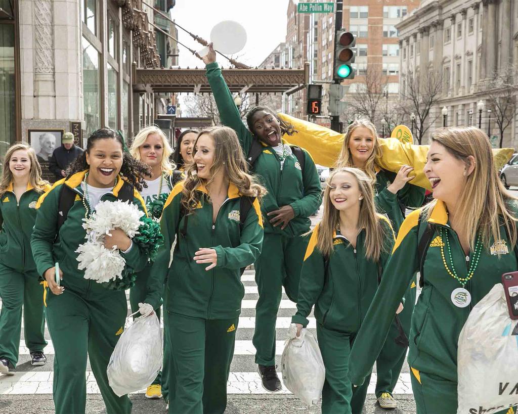 female students walking toward the camera wearing green and gold track suits