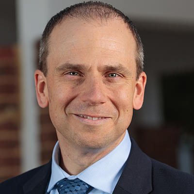 Smiling man with short hair wearing a navy suit