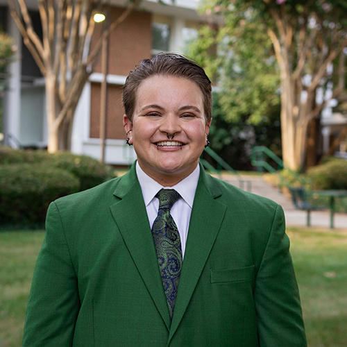 Young white male student dressed in a coat and tie poses for an outside photo