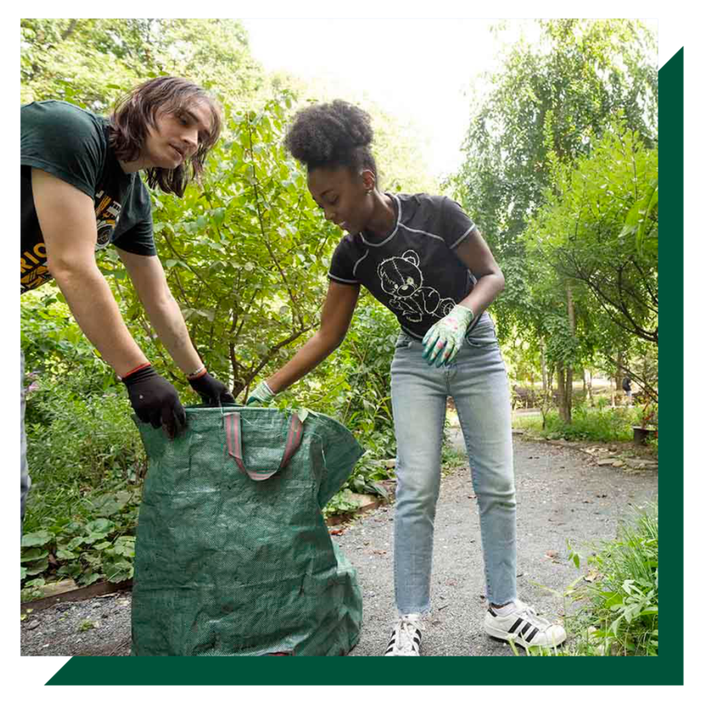 Two students clean up an outdoor trail.