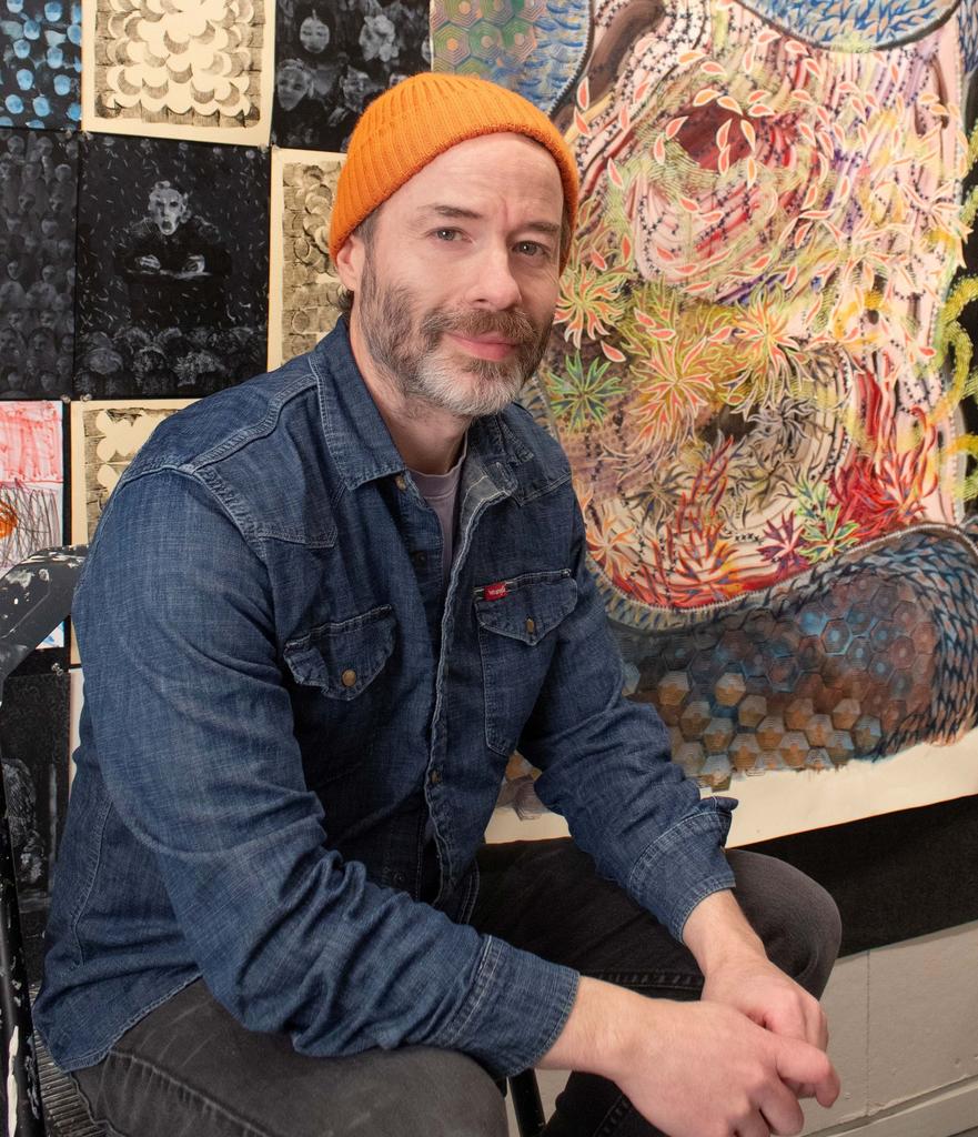 Jeffrey Kenney sits in front of his artwork