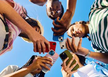 Students standing in a circle holding cell phones..