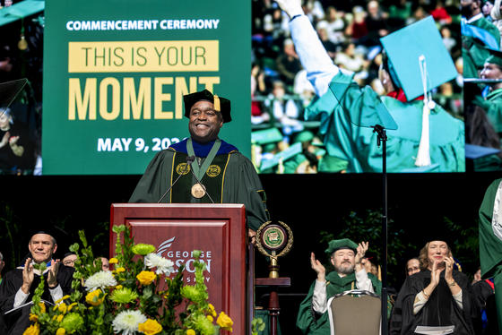 George Mason President Gregory Washington addresses the Spring 2024 Commencement crowd from the stage at EagleBank Arena