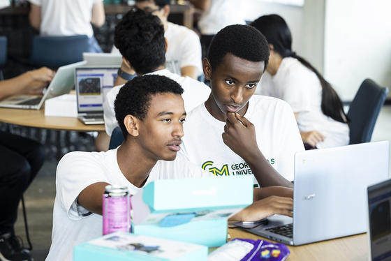 Two students share a laptop, trying to solve a problem