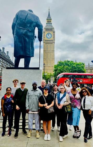 A group of students pose for a photo in London with a statue and Big Ben in the background