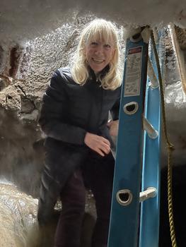Elise Miller-Hooks climbs down a ladder. Around the ladder, the walls are made of ice and permafrost.