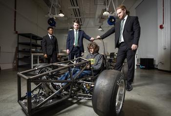 Students surrounding their wheeled vechicle prototype.